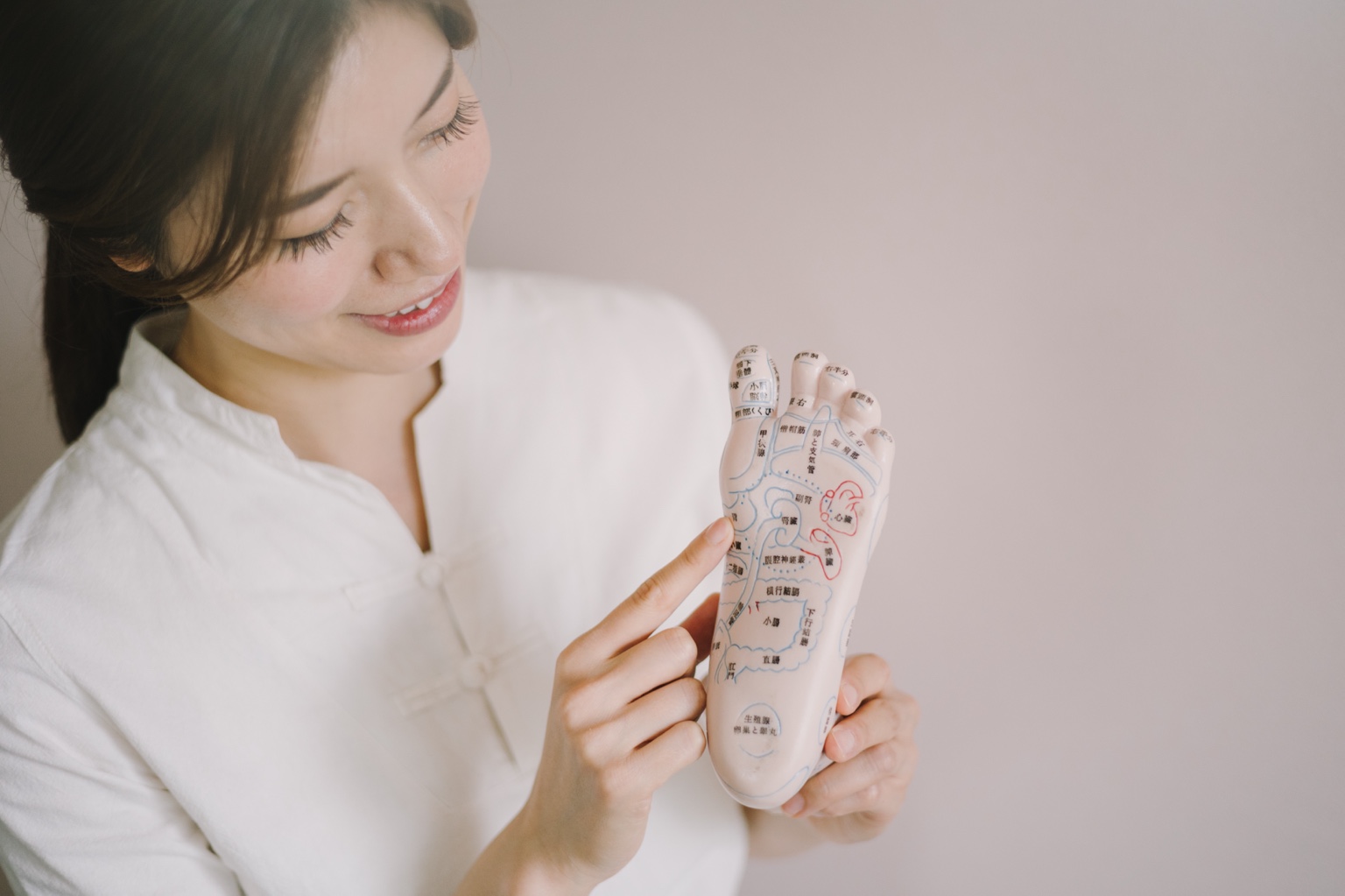 斉藤玲奈が足裏の模型を指し示す様子